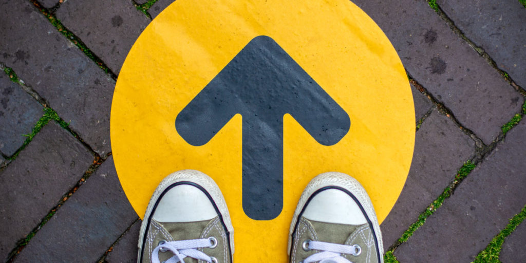 feet standing at an arrow pointing forward